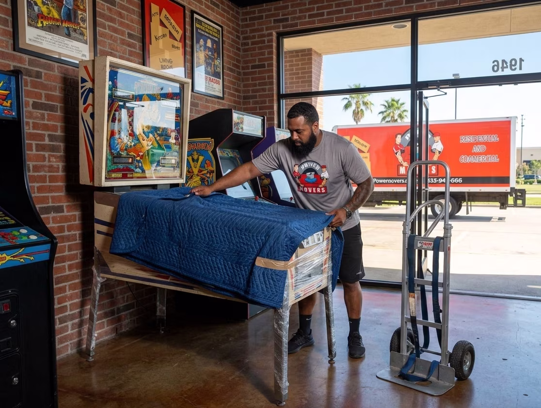A power movers team member is wrapping a pinball machine for a local moving in houston texas